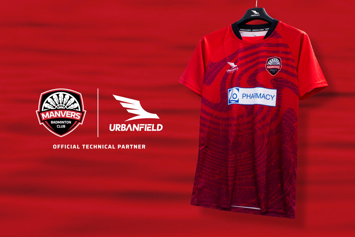 Manvers Badminton Club shirt on a black hanger in front of a red lake background.