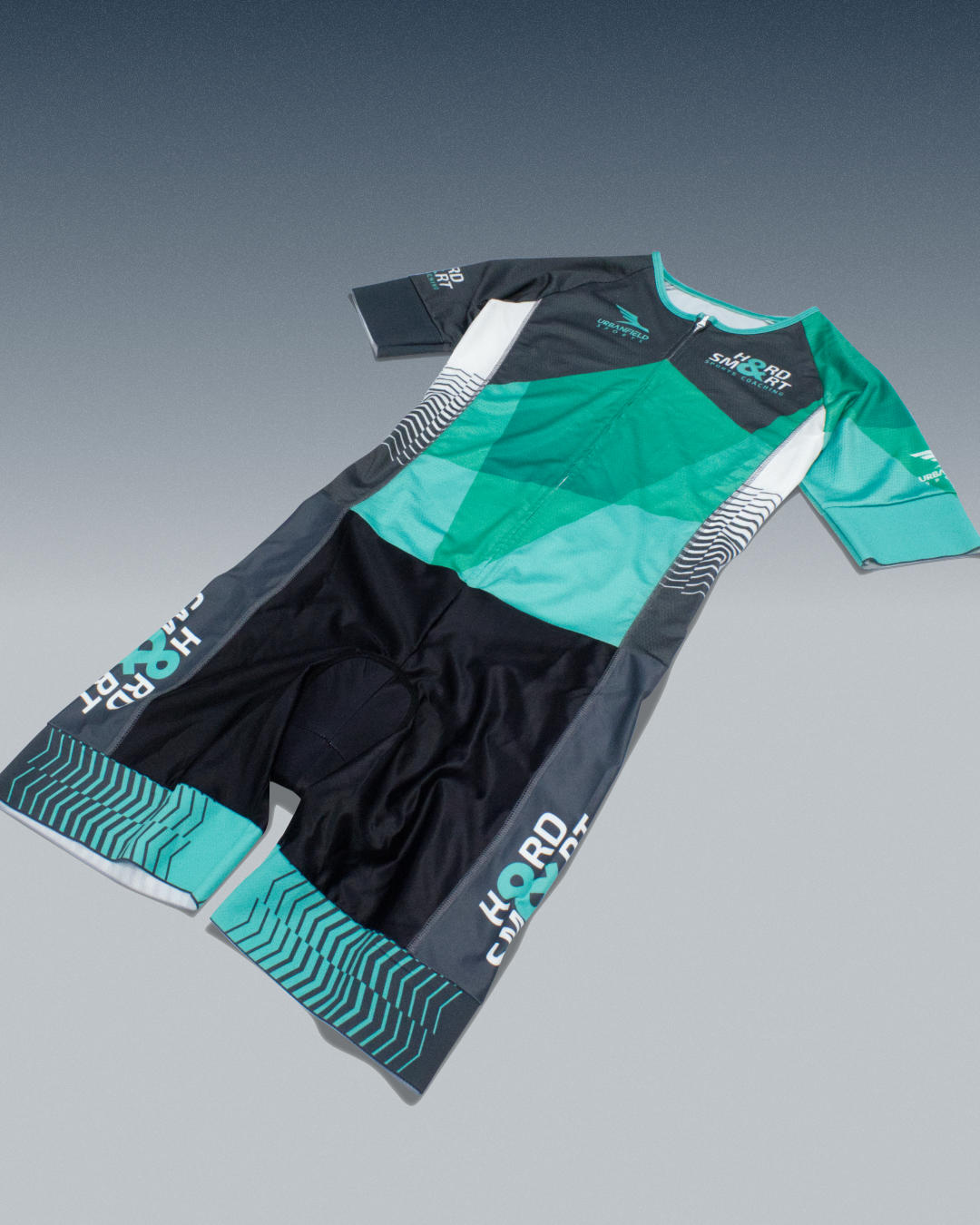 Hard & Smart Sports Coaching triathlon suit in mint green and graphite grey on a bluish grey background.