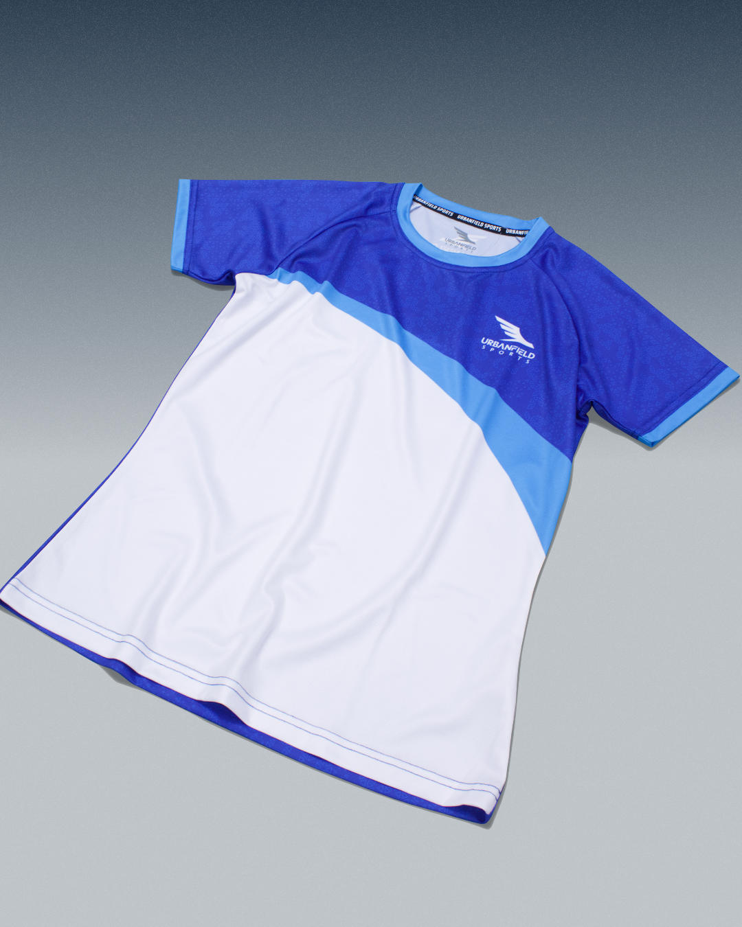 Women's Urbanfield Sports ace t-shirt in royal blue and cyan blue on a bluish grey background.