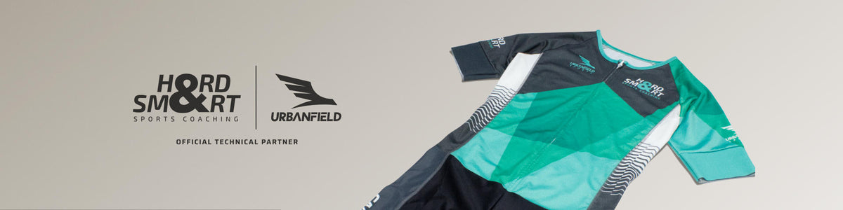 Hard & Smart Sports Coaching Tri Suit on a dark beige background.