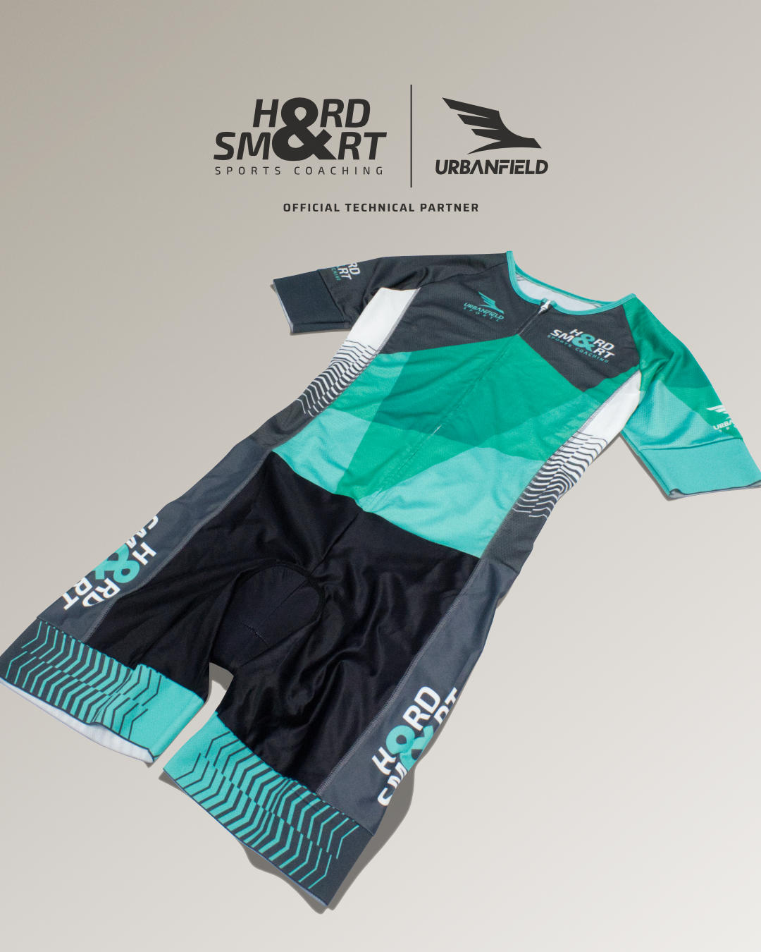 Hard & Smart Sports Coaching Tri Suit on a dark beige background.