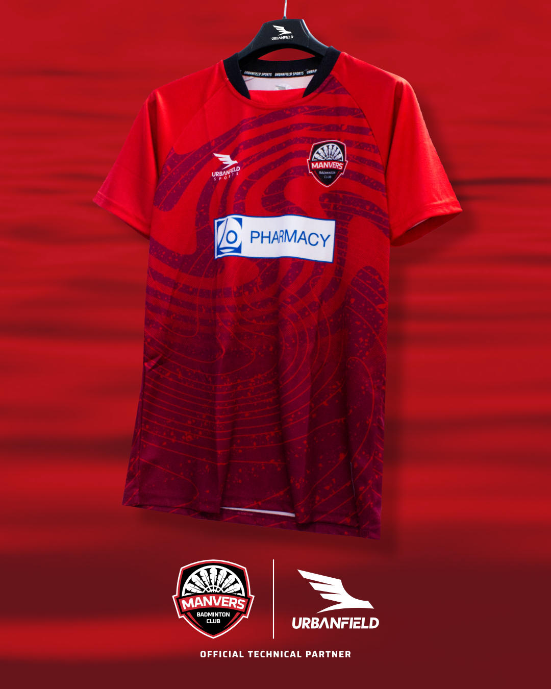 Manvers Badminton Club shirt on a black hanger in front of a red lake background.