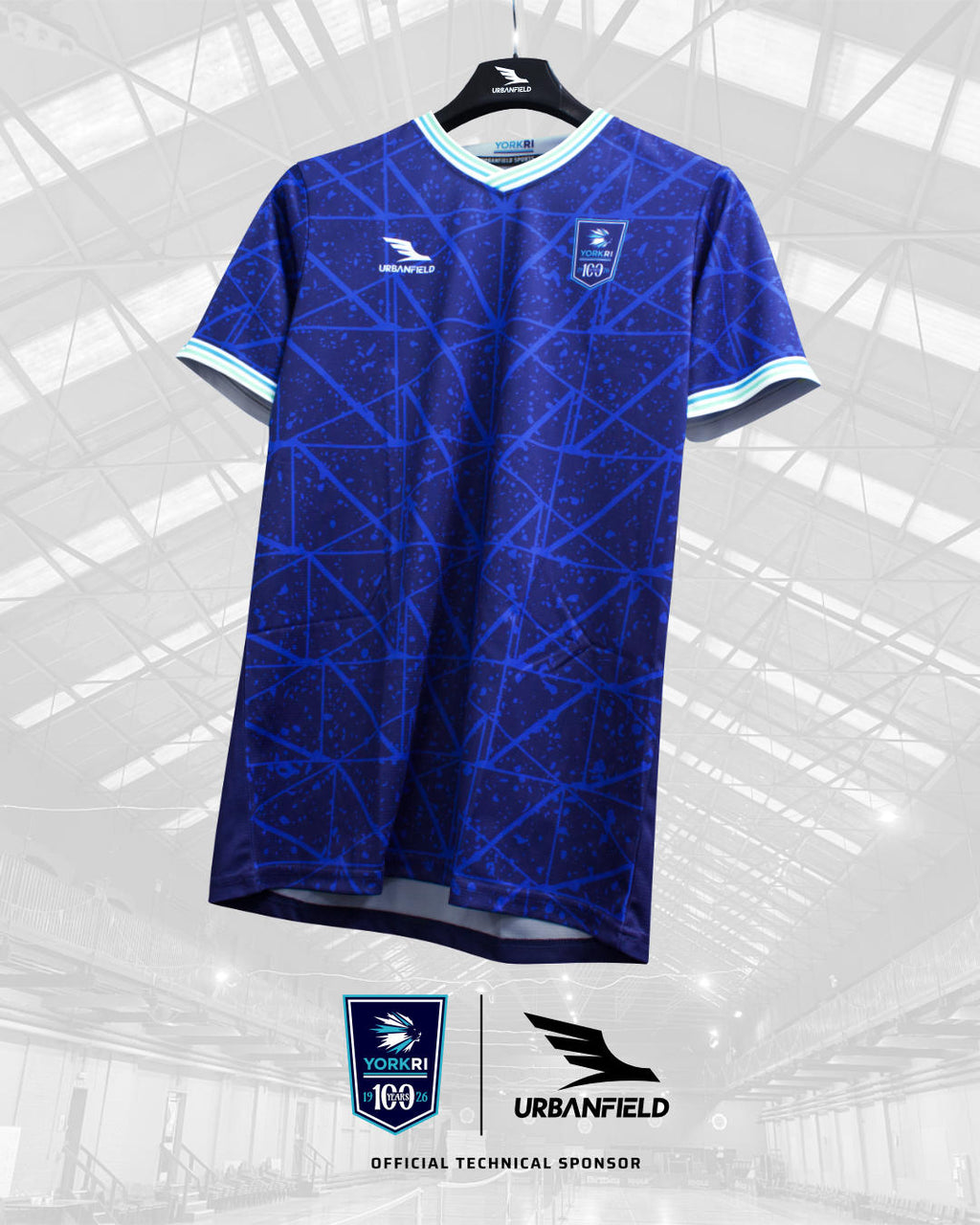 York RI Centenary shirt on a black Urbanfield Sports hanger in front of a white background featuring the York RI roof.